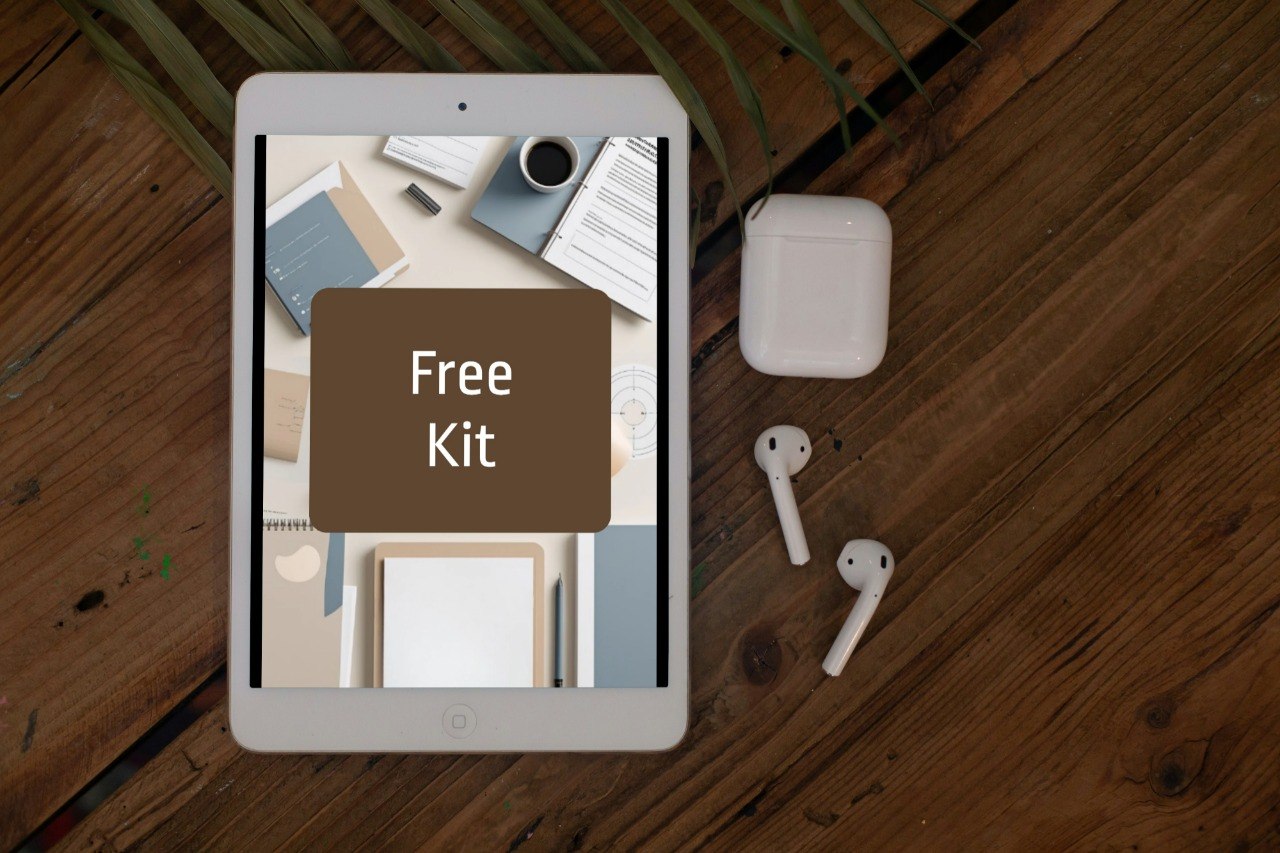 A tablet on a wooden table displaying a mockup of a free digital kit, accompanied by white wireless earbuds and a charging case. The tablet screen shows a brown card overlay reading 'Free Kit'.